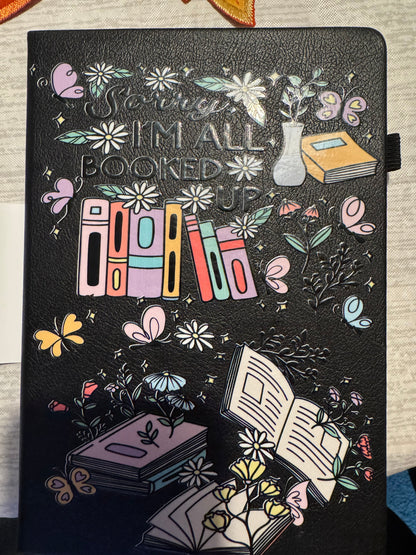 Black 5 x 7 leather journal with colorful books, flowers, butterflies, and I'm All Booked Up cover design