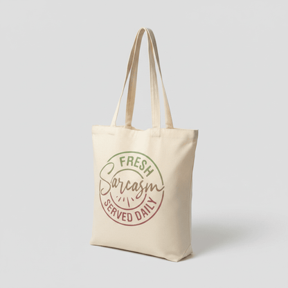 Funny canvas tote bag featuring the quote 'Fresh Sarcasm Served Daily' on natural canvas.